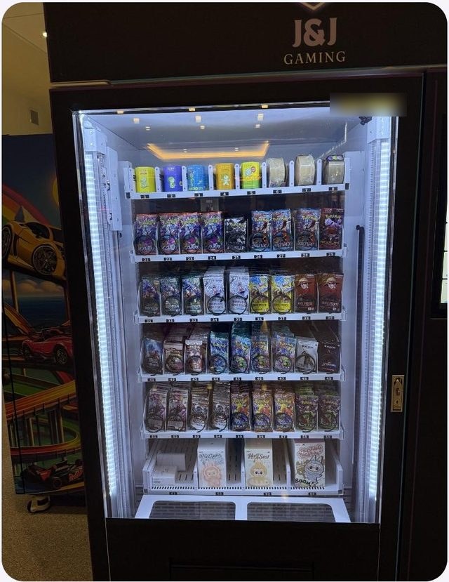 J&J collectibles machine with lit shelves of sealed trading card packs
